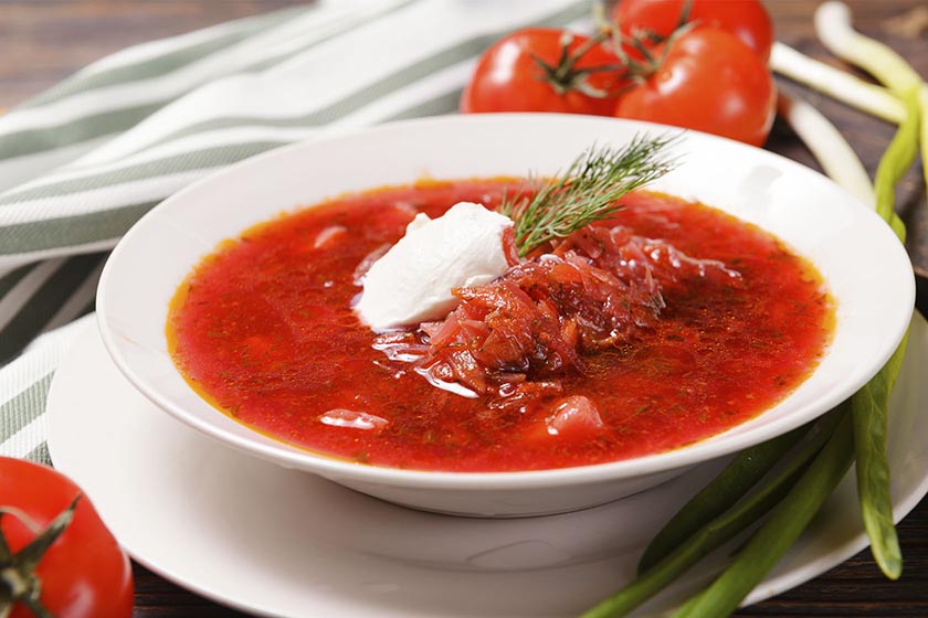 Bowl of red Beef Borscht topped with cream and fresh dill