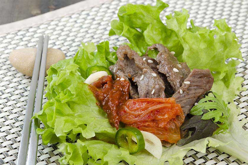Bulgogi Beef with sitting in a lettuce bowl on a table with chopsticks