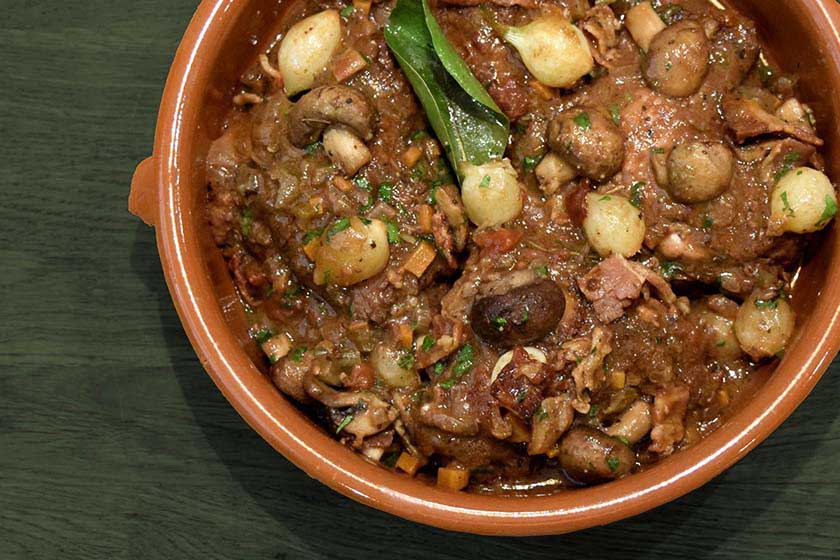 Chicken Coq au Vin in a bowl with baby onions and mushrooms