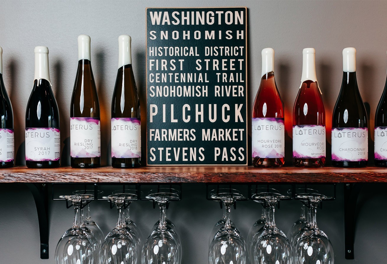 Lineup of Laterus wine bottles and a sign with famous Washington State destinations
