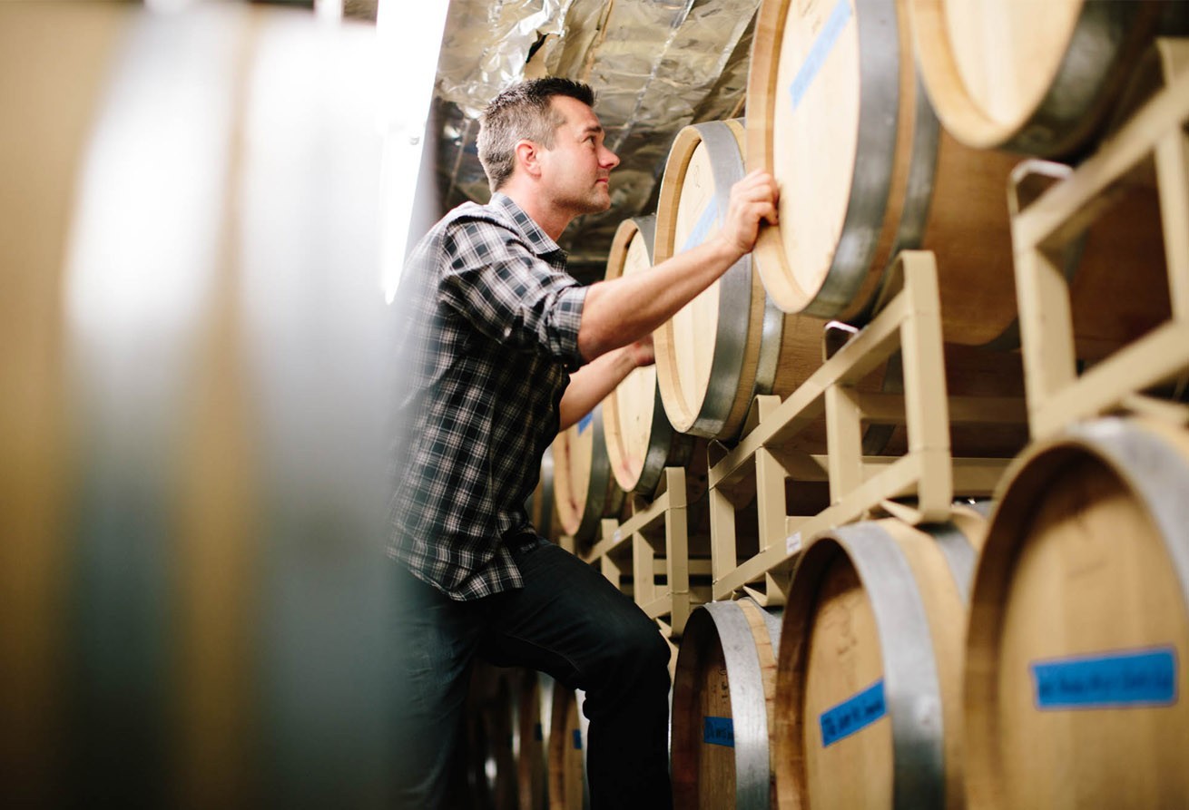 Winemaker, Morgan Lee, climbing between wine barrels