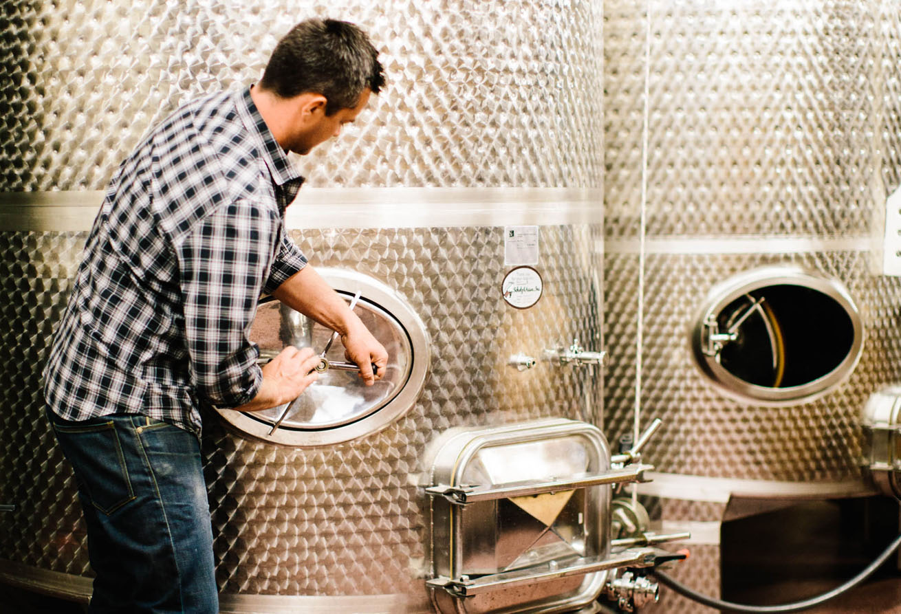 Two Vintners winemaker, Morgan Lee, checking stainless steel wine tank