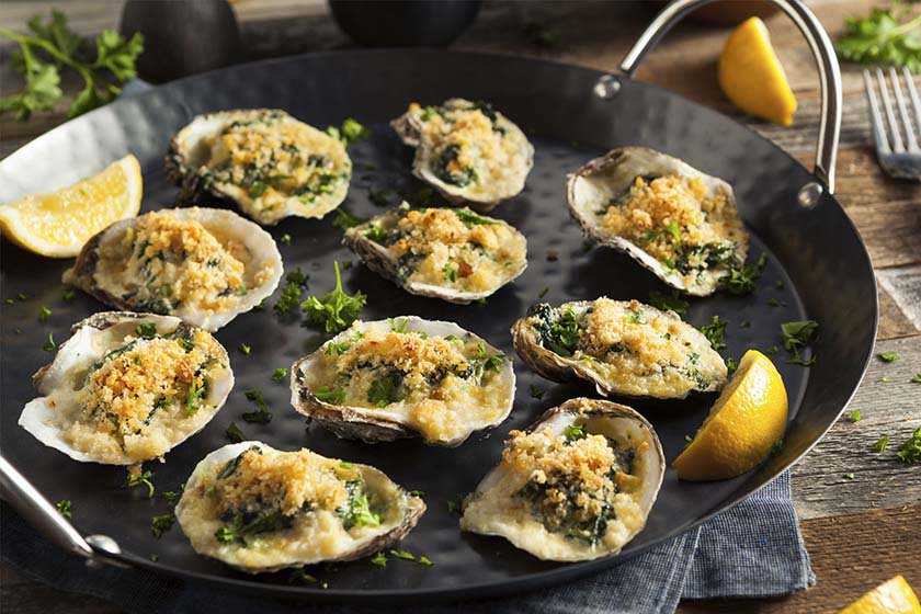 Baked oysters topped with breadcrumbs and parsley in a black pan