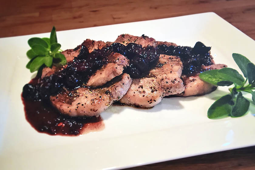 Pork chops topped with a cherry glaze on a white plate