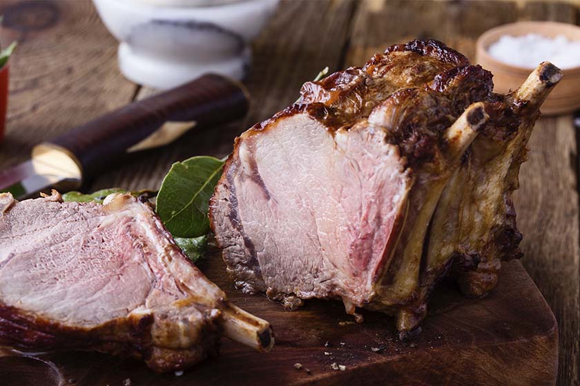 Juicy rib roast on the bone standing up on a wood cutting board