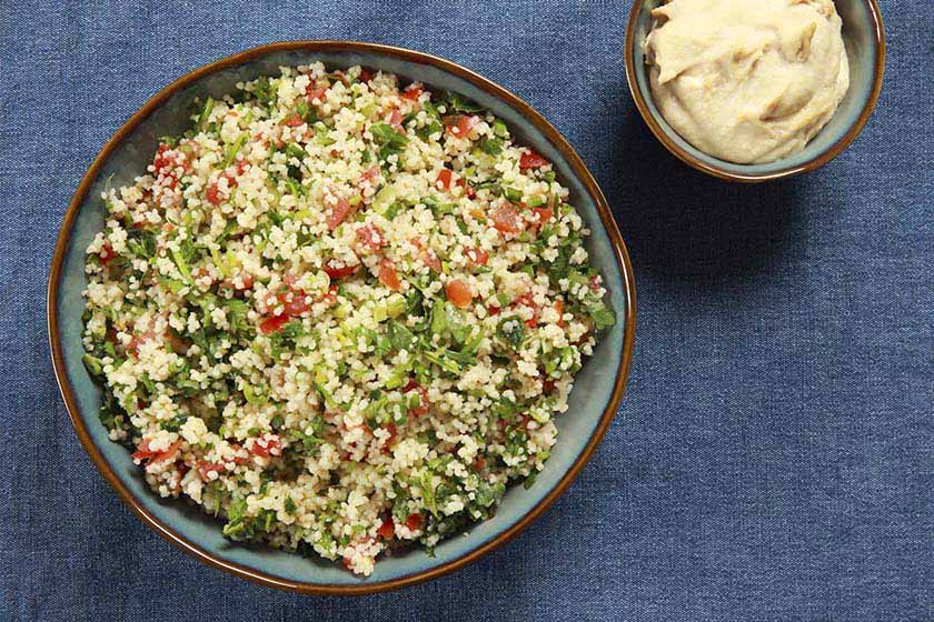 Bowl of bulgur wheat tabbouleh salad placed on a blue table cloth