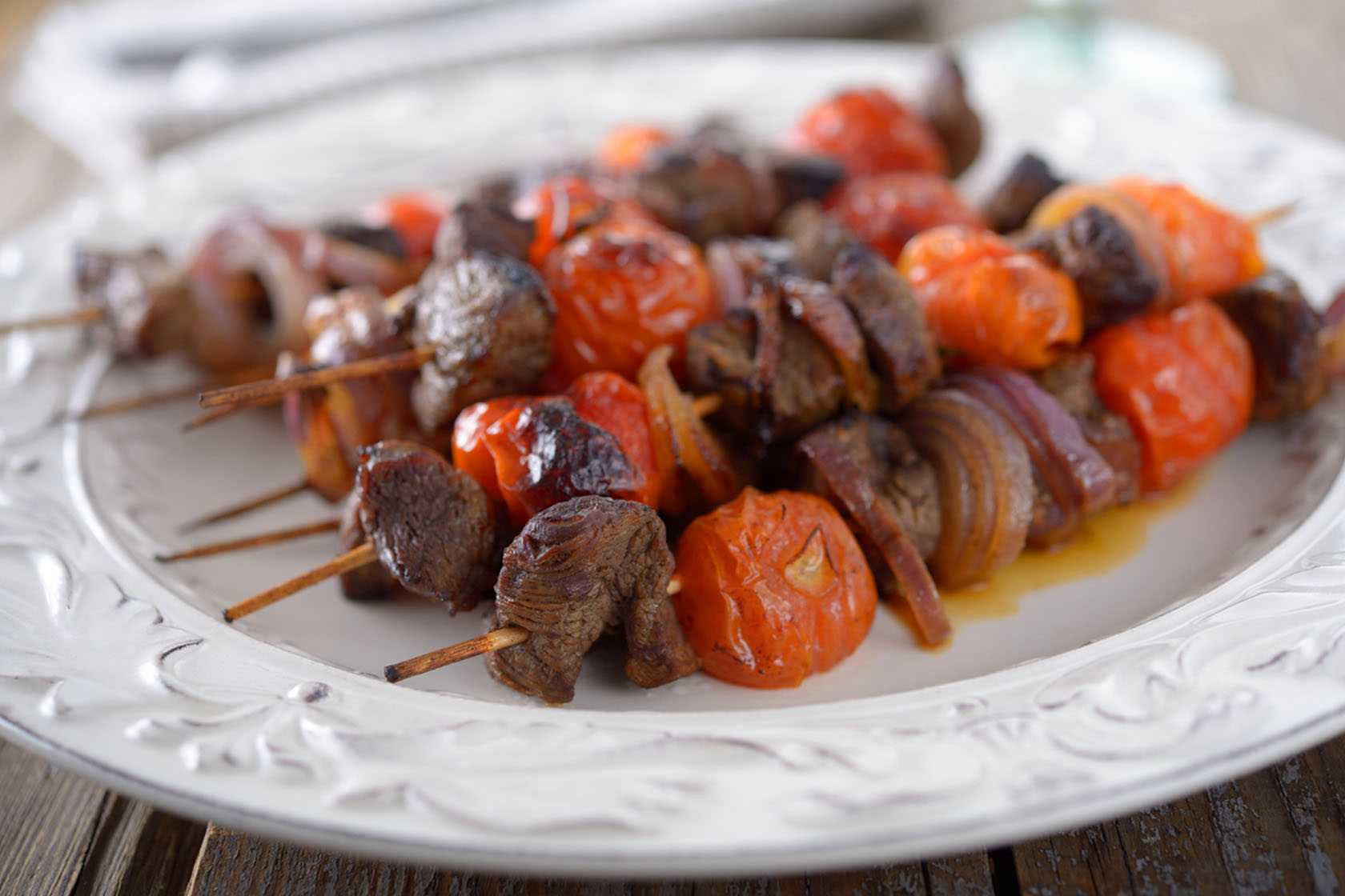 Mediterranean beef and tomato skewers on a white platter